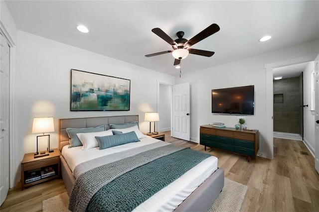 bedroom with ensuite bathroom, light wood-type flooring, and ceiling fan