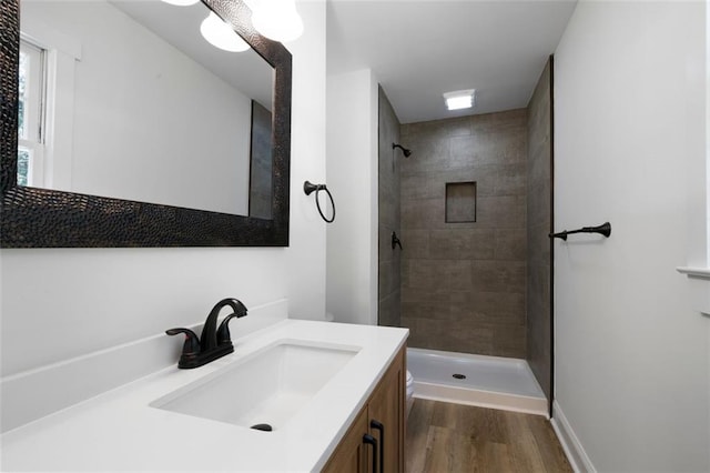 bathroom featuring a tile shower, vanity, and hardwood / wood-style floors