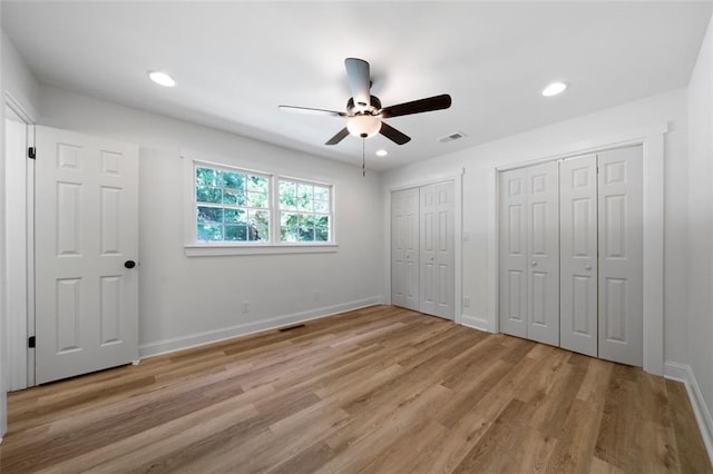 unfurnished bedroom featuring two closets, ceiling fan, and light wood-type flooring