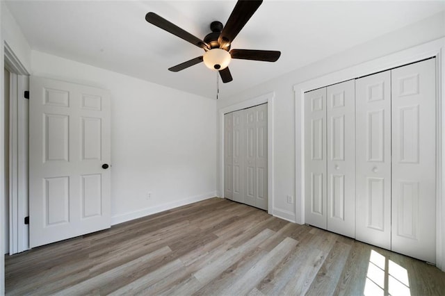 unfurnished bedroom with multiple closets, ceiling fan, and light wood-type flooring