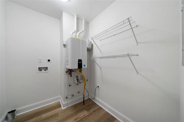 laundry area with hookup for a washing machine, hookup for an electric dryer, wood-type flooring, and tankless water heater