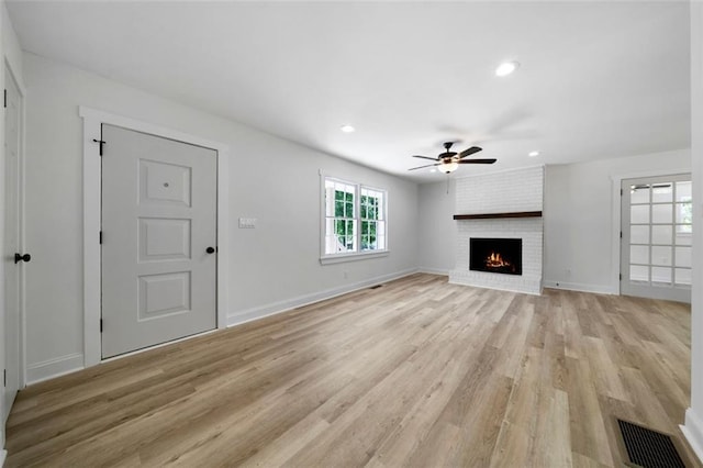 unfurnished living room featuring light hardwood / wood-style floors, ceiling fan, and a brick fireplace