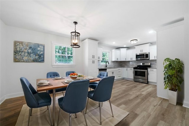 dining area featuring sink, an inviting chandelier, and light hardwood / wood-style floors