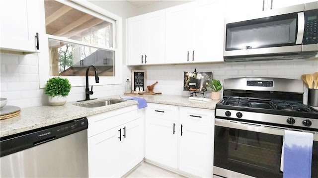 kitchen featuring backsplash, white cabinetry, sink, and appliances with stainless steel finishes