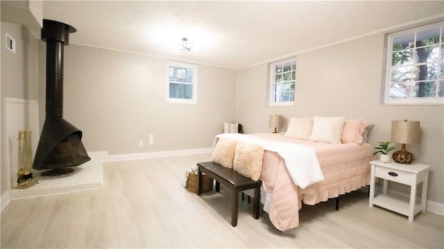 bedroom with crown molding, wood-type flooring, a wood stove, and multiple windows