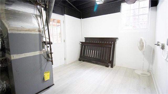 basement featuring hardwood / wood-style floors, a healthy amount of sunlight, and heating unit