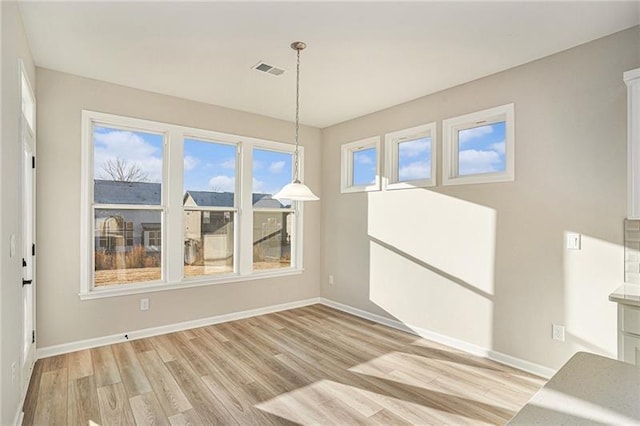 unfurnished dining area featuring light wood finished floors, baseboards, and visible vents