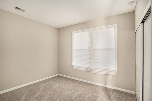 unfurnished bedroom with baseboards, carpet floors, visible vents, and a closet