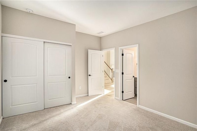 unfurnished bedroom featuring baseboards, a closet, visible vents, and carpet