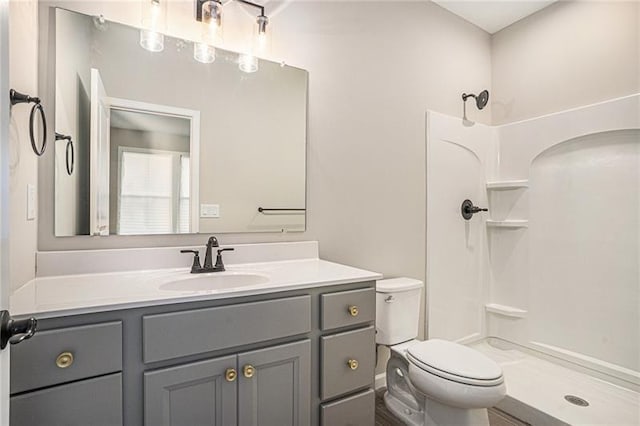 bathroom with vanity, a shower, and toilet