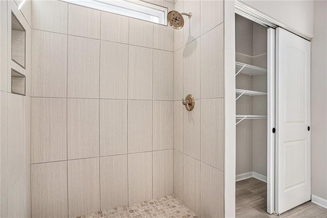 full bathroom featuring a tile shower and baseboards