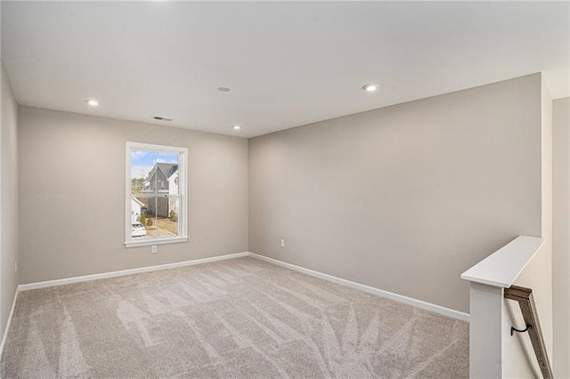 carpeted empty room featuring baseboards, visible vents, and recessed lighting