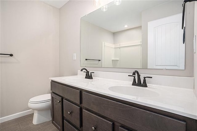 bathroom featuring baseboards, a sink, double vanity, and toilet