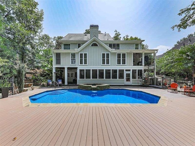 view of swimming pool featuring a patio, fence, a pool with connected hot tub, a sunroom, and a deck