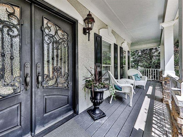 property entrance featuring covered porch and stucco siding