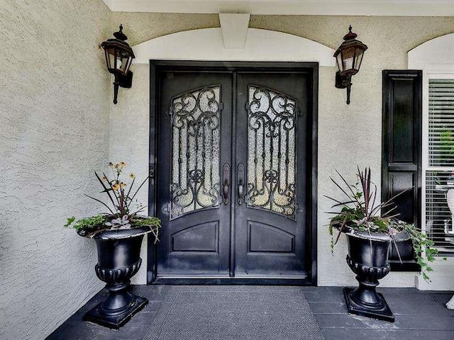 property entrance with stucco siding and french doors