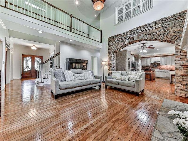 living area featuring visible vents, arched walkways, a ceiling fan, and light wood finished floors