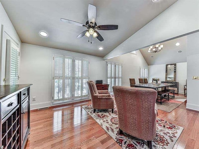 living room with light wood-type flooring, visible vents, ceiling fan with notable chandelier, baseboards, and vaulted ceiling