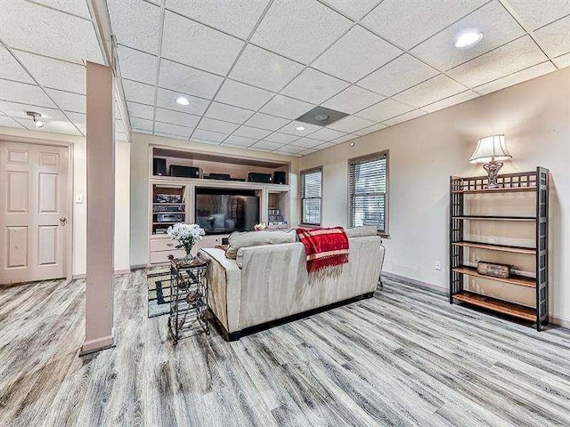 living area featuring wood finished floors, baseboards, and a drop ceiling