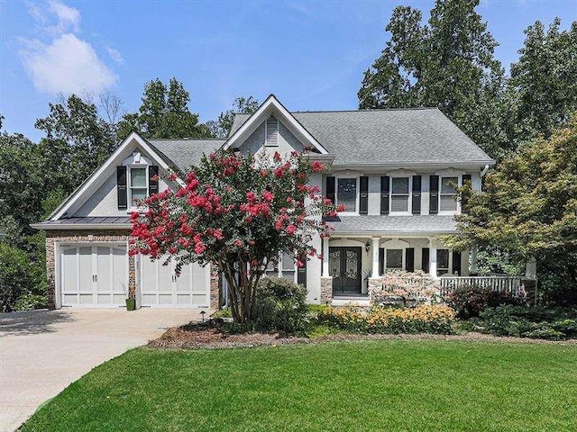 view of front of house featuring french doors, a garage, concrete driveway, and a front lawn