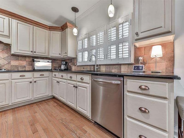 kitchen with a sink, hanging light fixtures, stainless steel dishwasher, dark countertops, and light wood-type flooring