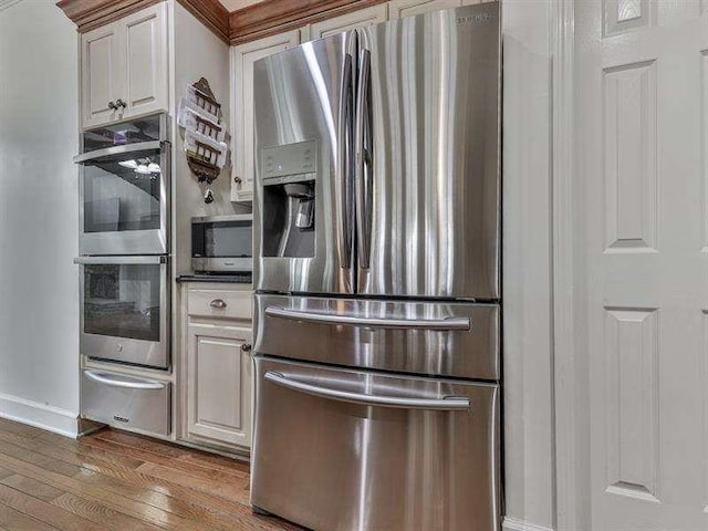 kitchen featuring a warming drawer, dark countertops, white cabinetry, stainless steel appliances, and wood-type flooring