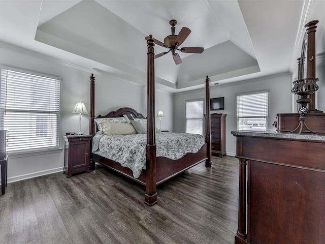 bedroom featuring ceiling fan, baseboards, dark wood-type flooring, and a tray ceiling