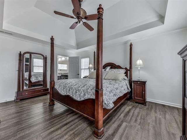 bedroom with a raised ceiling, wood finished floors, and baseboards