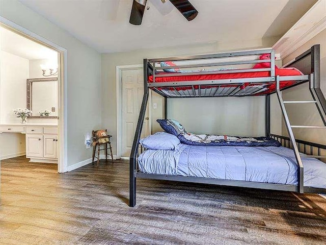 bedroom with baseboards, ensuite bath, wood finished floors, and a ceiling fan