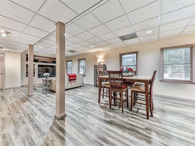 dining space featuring a paneled ceiling, baseboards, and wood finished floors