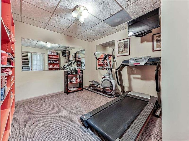 exercise room featuring a drop ceiling, baseboards, and carpet floors