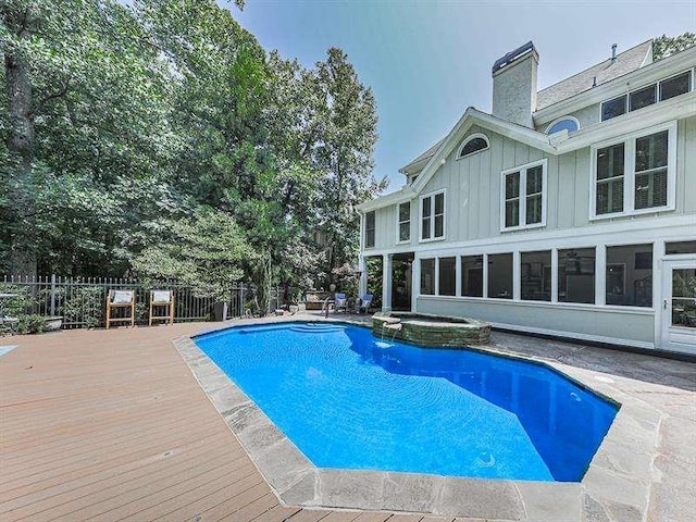 view of swimming pool with a wooden deck, a pool with connected hot tub, and fence