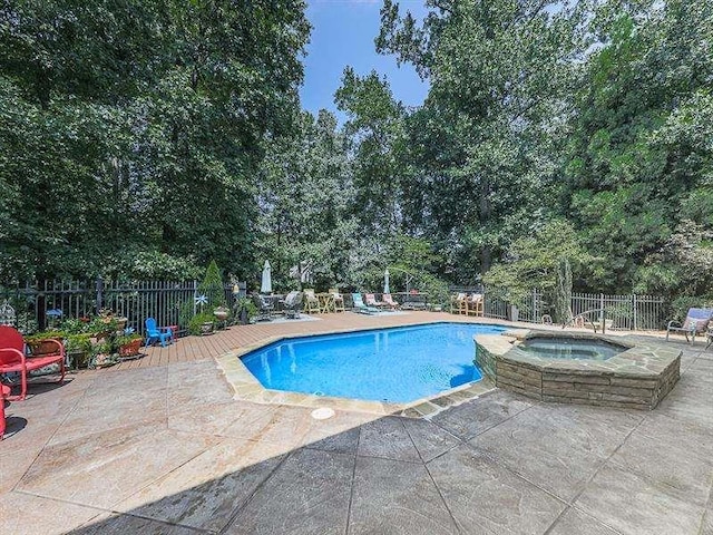 view of pool featuring a patio area, fence, and a pool with connected hot tub