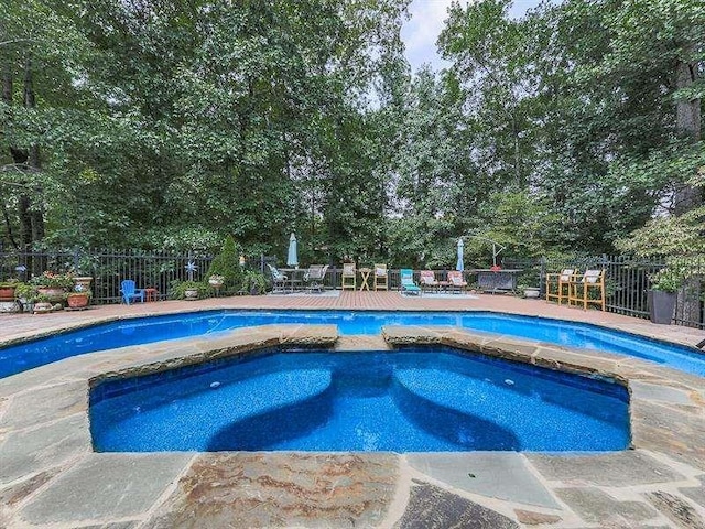 pool featuring a patio area, an in ground hot tub, and fence