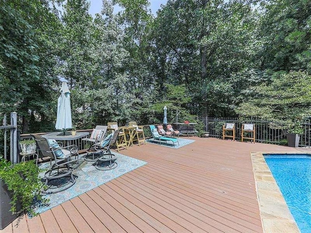 wooden deck with an outdoor pool and fence