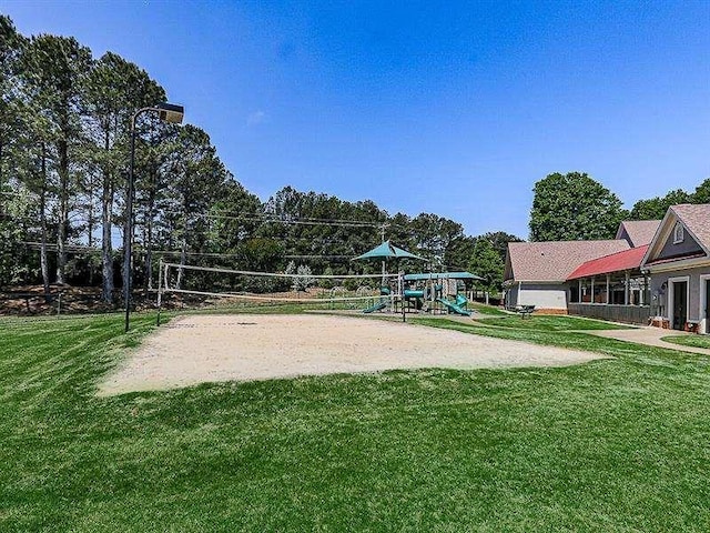 view of property's community with volleyball court, playground community, and a yard