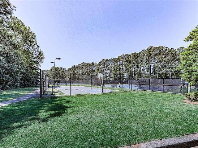 view of tennis court featuring fence and a lawn