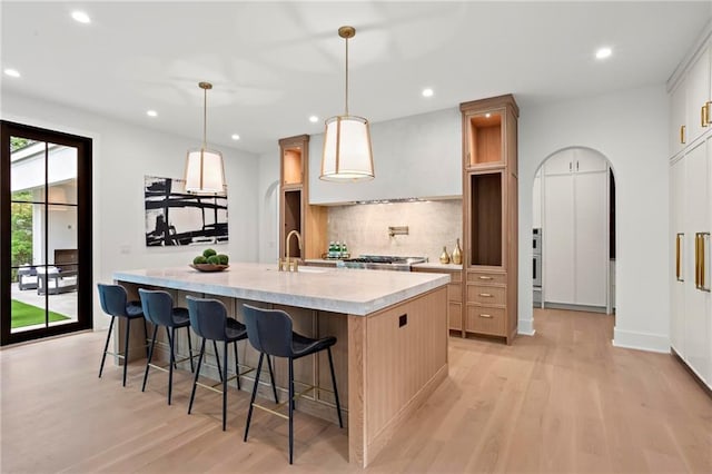4785 Merlendale Ct, Atlanta, GA 30327 - kitchen featuring light wood finished floors, light countertops, backsplash, recessed lighting, and an island with sink