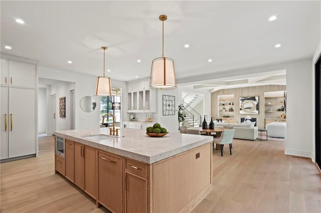 4785 Merlendale Ct, Atlanta, GA 30327 - kitchen featuring a sink, light wood-style floors, a kitchen island with sink, recessed lighting, and light stone countertops