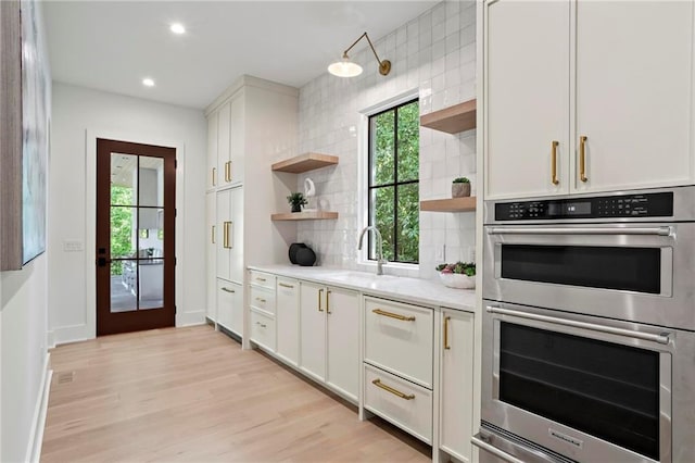 4785 Merlendale Ct, Atlanta, GA 30327 - kitchen with open shelves, stainless steel double oven, a sink, tasteful backsplash, and light wood-style flooring