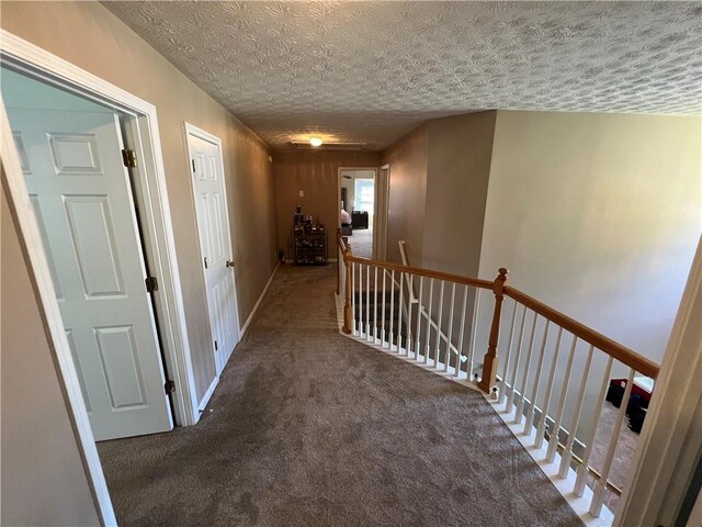 corridor with a textured ceiling and dark carpet