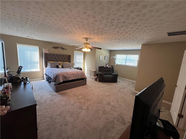 bedroom with a textured ceiling, light colored carpet, and ceiling fan