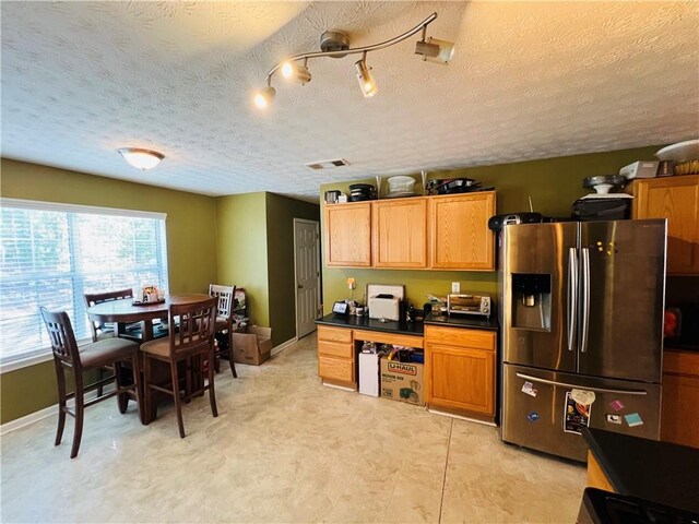 kitchen with stainless steel refrigerator with ice dispenser and a textured ceiling