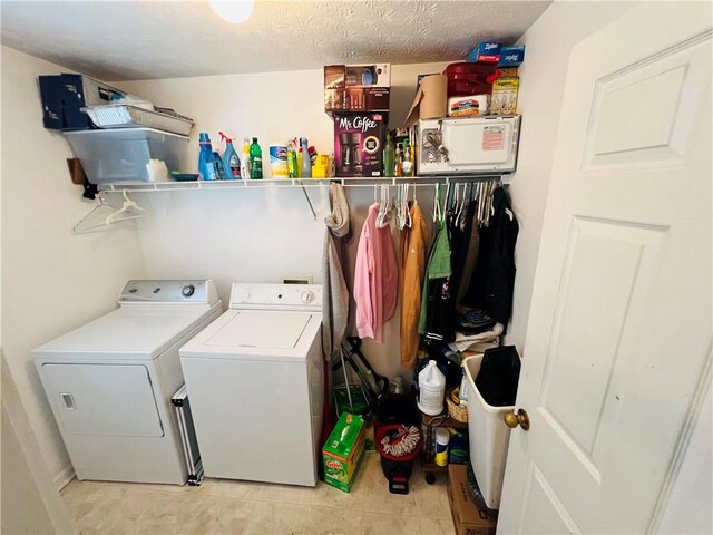 washroom featuring a textured ceiling, washer and clothes dryer, and light tile patterned flooring