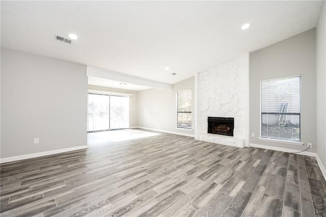 unfurnished living room featuring hardwood / wood-style floors and a stone fireplace