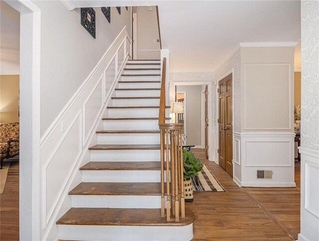 living room featuring a brick fireplace, an inviting chandelier, ornamental molding, and hardwood / wood-style flooring