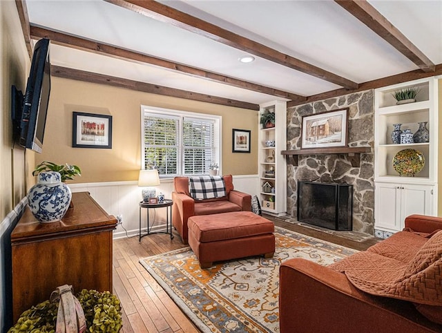 living room with a fireplace, beamed ceiling, built in features, and hardwood / wood-style flooring