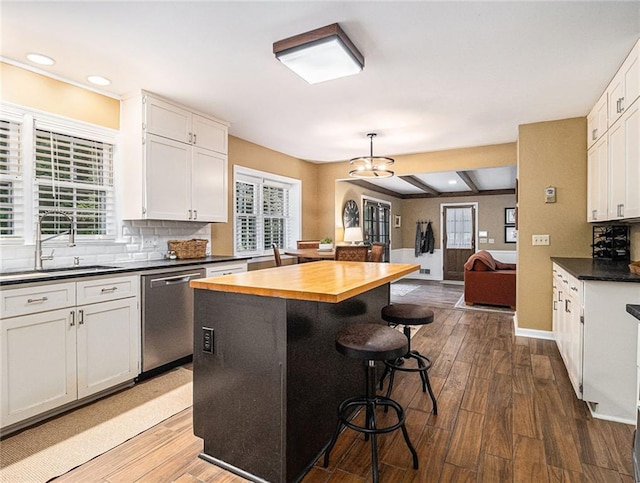 kitchen with hardwood / wood-style floors, white cabinets, stainless steel dishwasher, and a kitchen island