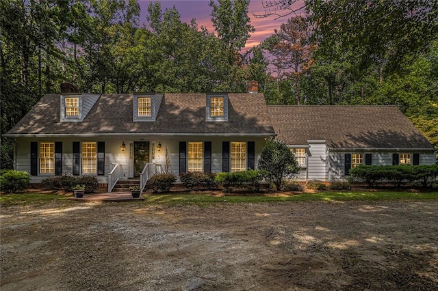 cape cod-style house featuring covered porch