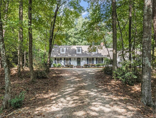 cape cod-style house featuring covered porch and a front lawn